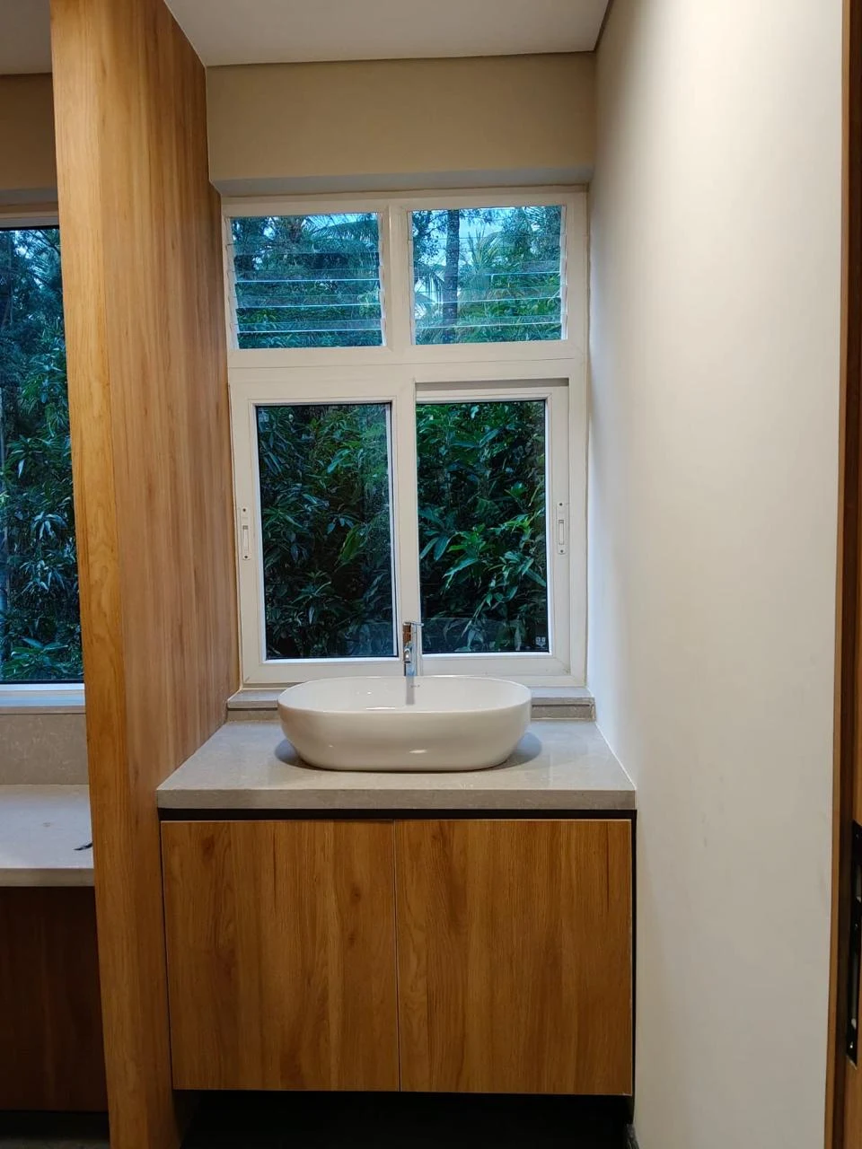 Basin and timber vanity beneath a tall window