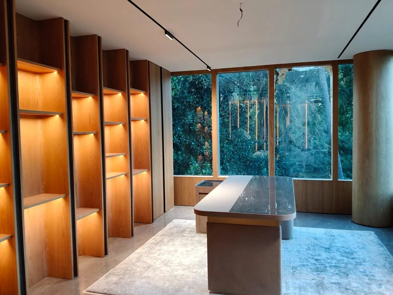 Interior with warmly illuminated shelving, central table and glazing