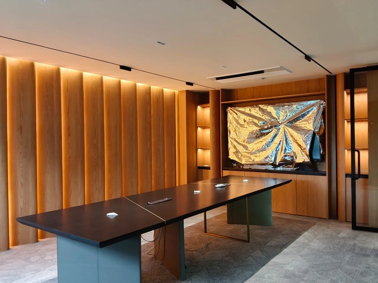 Interior with illuminated timber panelling and a dark feature table